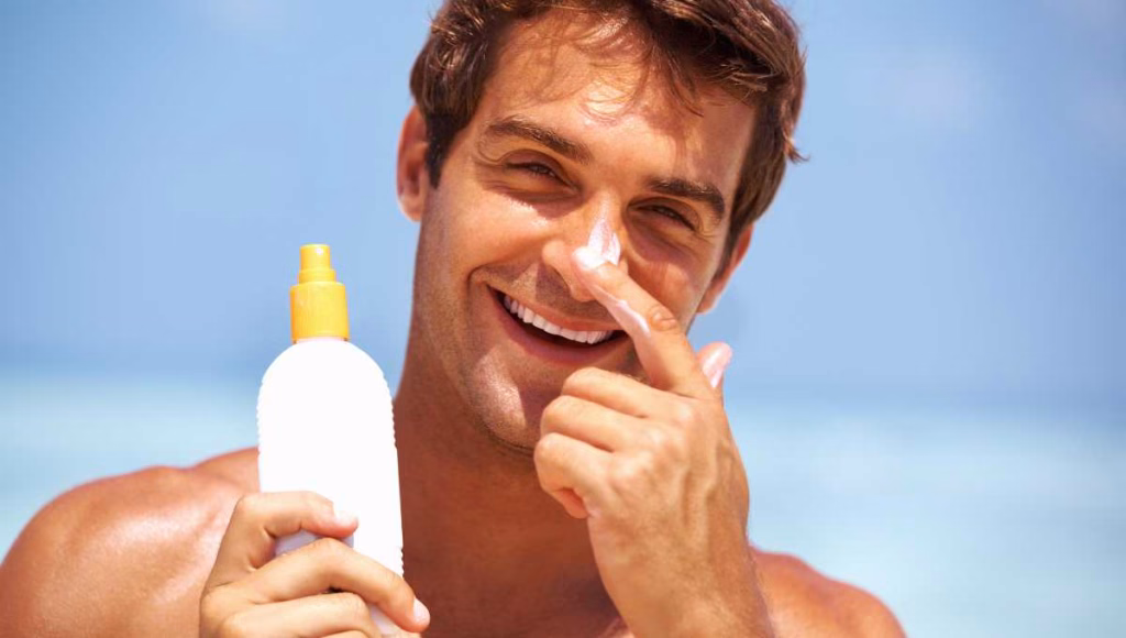 A man applying sunscreen on his face