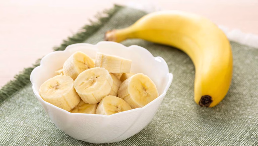 Sliced ripe bananas in a bowl on a wooden surface
