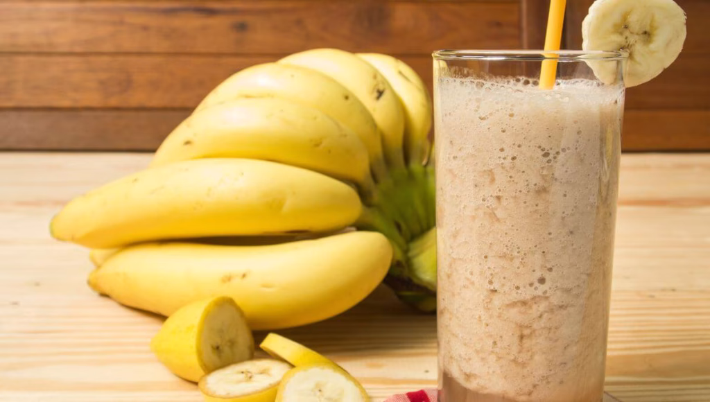 A glass of banana shake next to ripe bananas